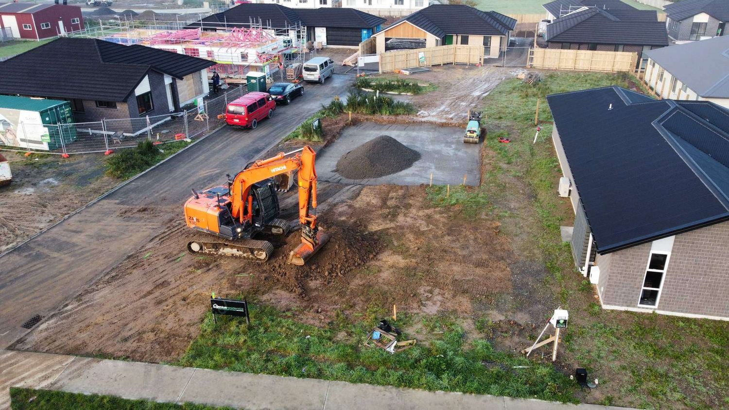 Drone view of an excavator and a pile of metal on a residential section in a new subdivision