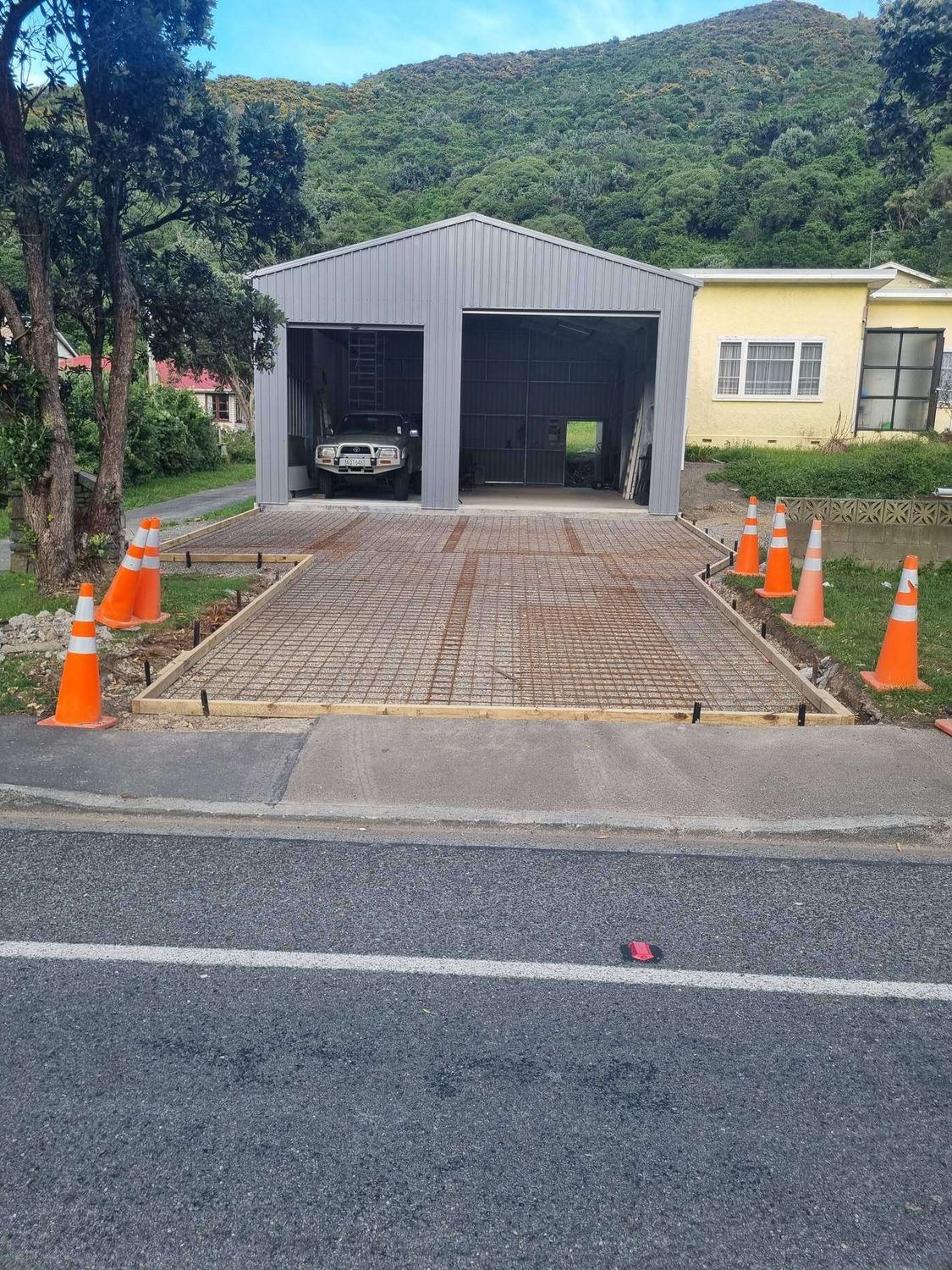 Driveway boxed and meshed for concrete in front of a double garage, with road cones out