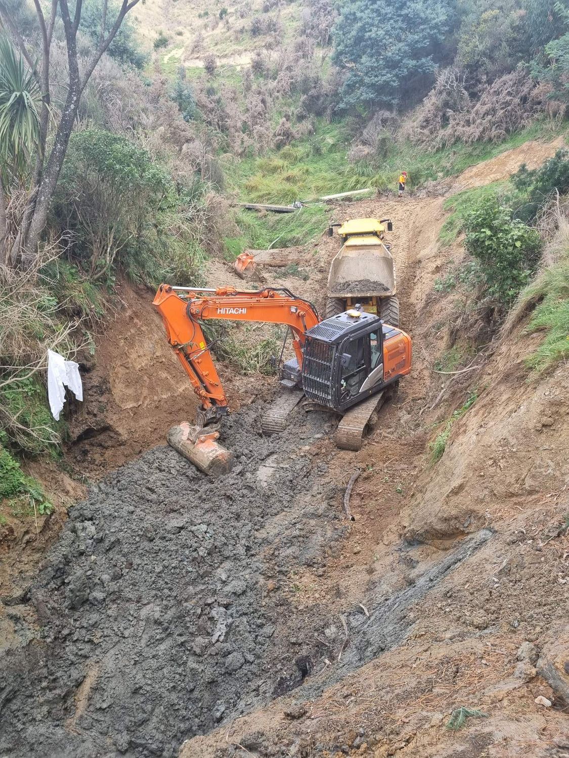 Excavator and tracked dumper working their way down a steep gully