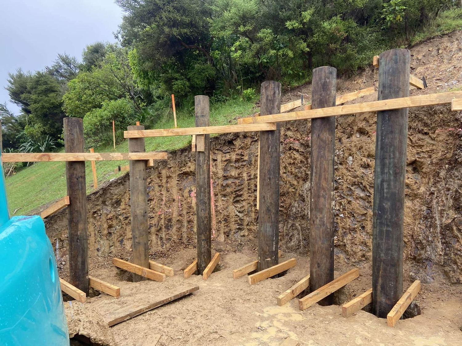 Timber pole retaining wall with temporary walers on a cut bank