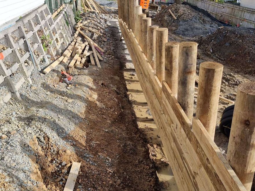 Timber retaining wall with drainage gravel behind it, built along the side of a house